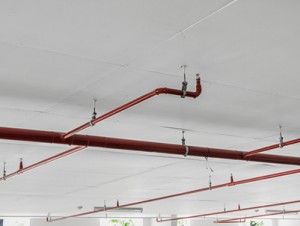 Fire sprinkler and red pipe on white ceiling background